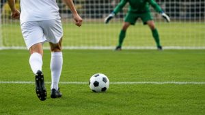 Jogador se prepara para cobrar um pênalti em campo de futebol, em imagem ilustrativa gerada por IA.