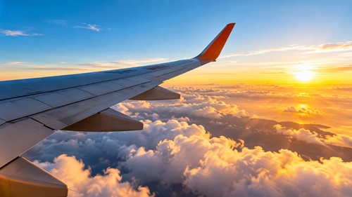 Asa de avião durante voo entre nuvens para ilustrar promoção de passagens aéreas