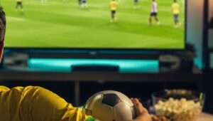Pessoa assistindo partida de futebol pela televisão em casa