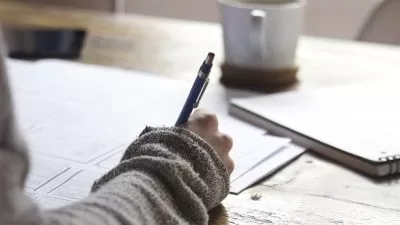Pessoa escrevendo em um caderno com uma caneta