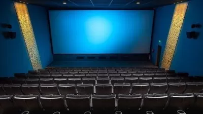 Sala de cinema vazia com poltronas e tela de projeção em ambiente escuro