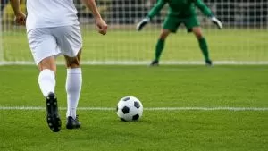 Jogador se prepara para cobrar um pênalti em campo de futebol, em imagem ilustrativa gerada por IA.
