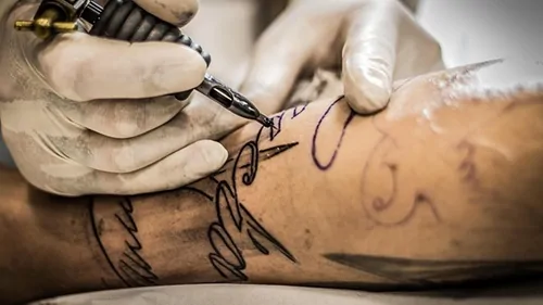 Tatuador realizando trabalho de tatuagem