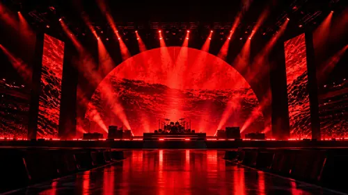Palco de show com iluminação vermelha, instrumentos e estrutura de som, sem público ou músicos.
